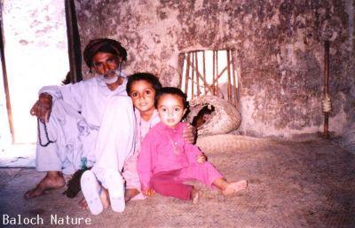 A Baloch family 
بلوچ کہول
Baloch Kahol
اے بلوچ ءِ گوں وتی چُکاں لوگ ءَ نیشتگ۔ بلے ہمے لوگ ءَ دریگ ءِ دپ ءَ نکینک سُند ءَ انت ءُ پنّاستگ ۔ بلوچ تنیگہ انچو پدمنتگ انت کہ مجبور انت کہ گوں ھیواناں ھور وھد بوگوازین ات ۔ 
